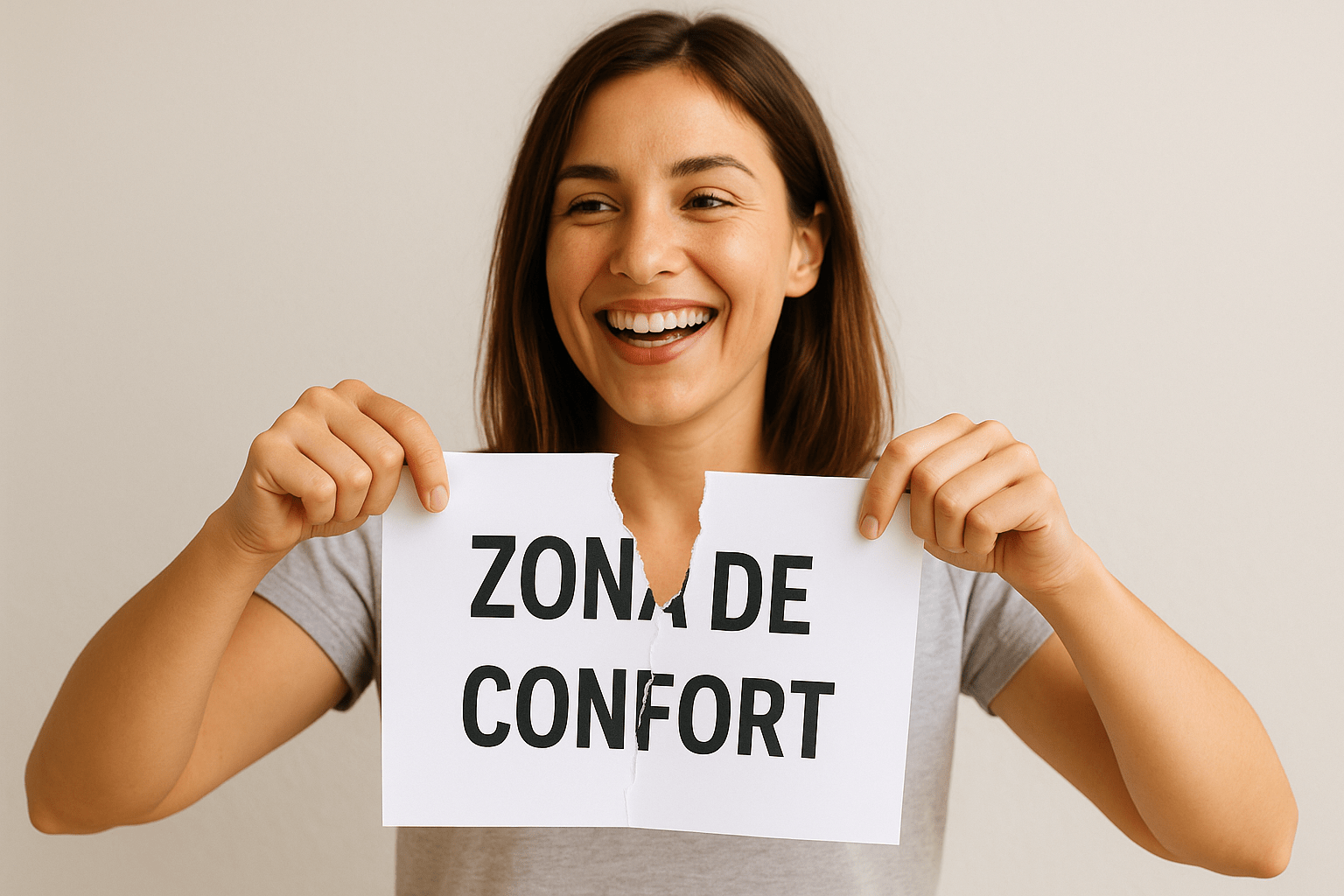 Una mujer sonriente rompe un papel en el que está escrita en español la frase “ZONA DE CONFORT”, simbolizando decisión y motivación.