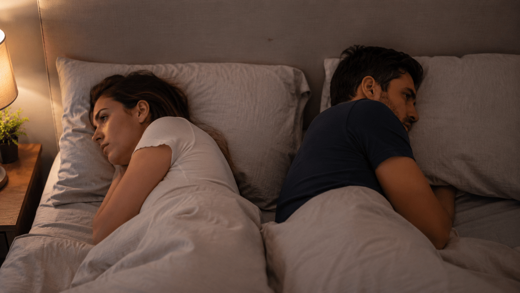 pareja acostada dándose la espalda en una cama, reflejando distancia emocional, soledad afectiva y falta de conexión emocional dentro de la relación